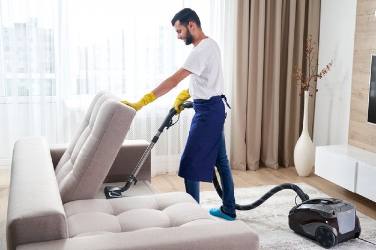 young-man-cleaning-sofa-with-vacuum-cleaner-leaving-room-home_130111-3594